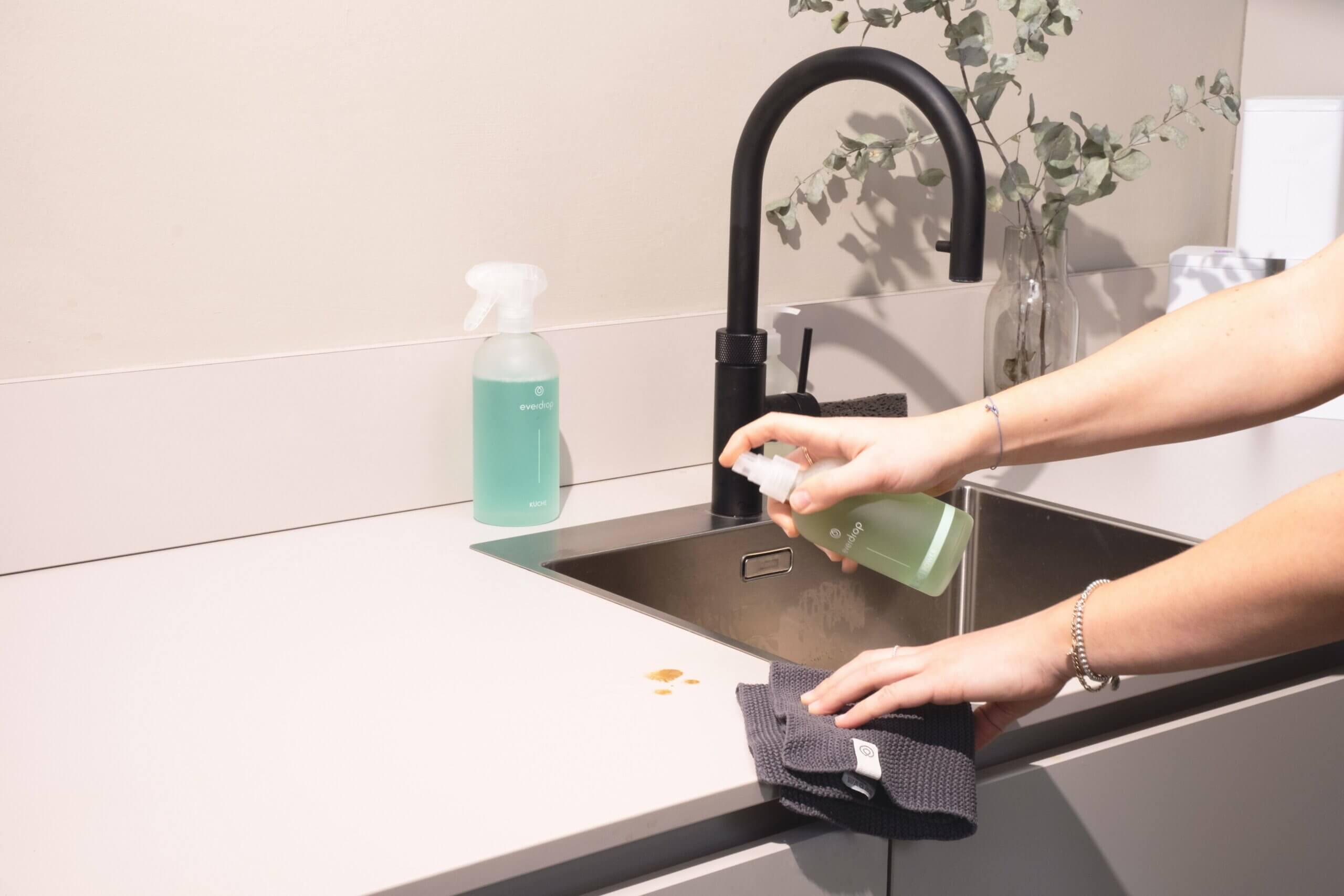 Person cleaning a countertop with deep sink